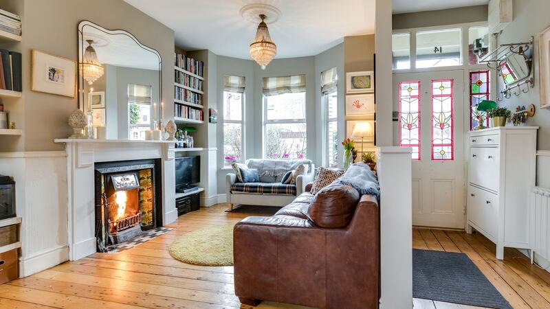The open-plan living space in the  front of the house, features a tiled fireplace and original wooden flooring