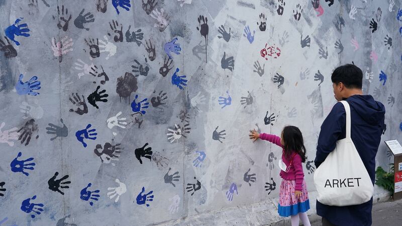 A little girl places her hand on a mural at the East Side Gallery, a section of the former Berlin Wall that is covered in street art. Photograph: Sean Gallup/Getty Images