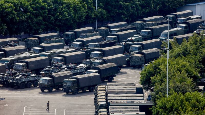 Servicemen walk past military vehicles in the parking area of the Shenzhen Bay Sports Centre in Shenzhen, across the bay from Hong Kong, on Friday. Photograph: Thomas Peter/Reuters