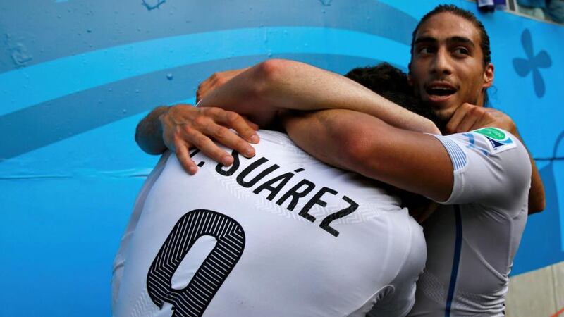 Uruguay's Luis Suarez (L) and Martin Silva (R) hug their teammate Diego Godin (not visible) after he scored a goal against Italy during their 2014 World Cup Group D soccer match at the Dunas arena in Natal June 24, 2014.  REUTERS/Toru Hanai (BRAZIL - Tags: SOCCER SPORT WORLD CUP)