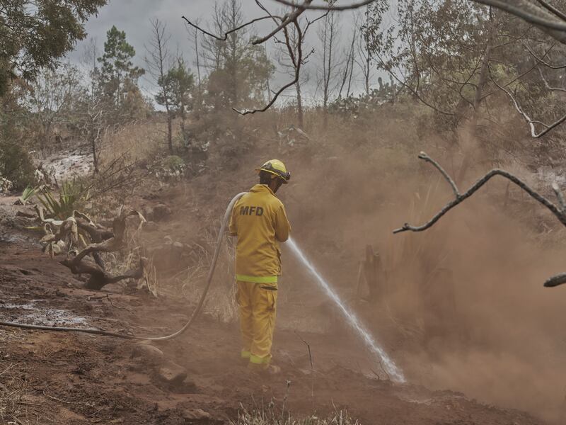 Firefighters spray water on hot spots in Kula, Maui, Hawaii, on Sunday. Photograph: Philip Cheung/New York Times