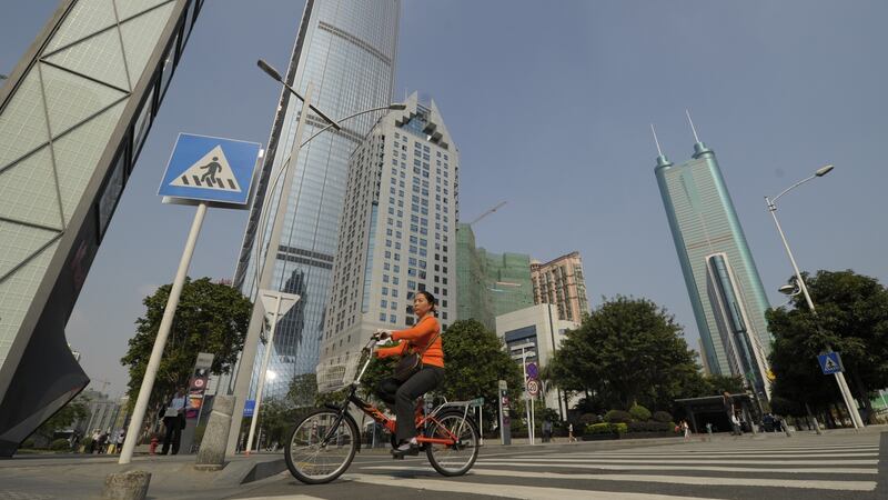 A cyclist crosses a road between skyscrapers in the southern Chinese city of Shenzhen. Photograph:  PETER PARKS/AFP/Getty Images)