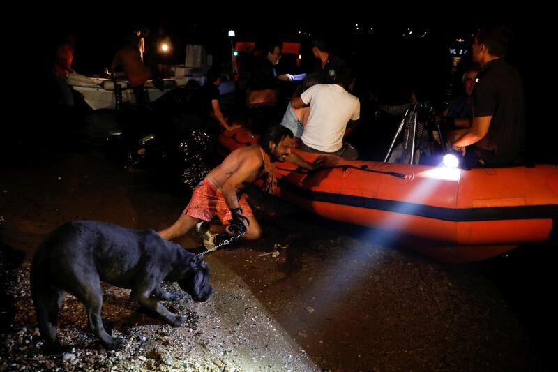 A man holding a dog pushes an inflatable boat as locals are evacuated during a wildfire at the village of Mati. Photograph: REUTERS/Alkis Konstantinidis