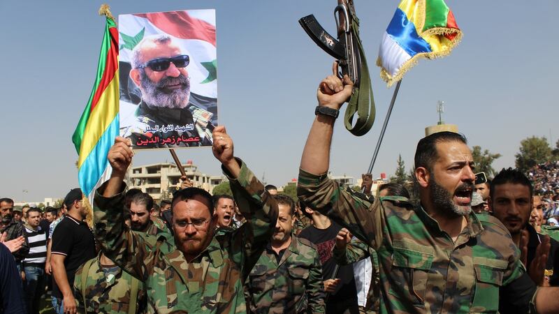 Syrian officers hold up photos of Maj Gen Issam Zahreddine, a prominent Syrian general known for his fight against Islamic State  who was killed in recent days, at the National Stadium Square in the southern province of al-Sweida, Syria. Photograph: EPA
