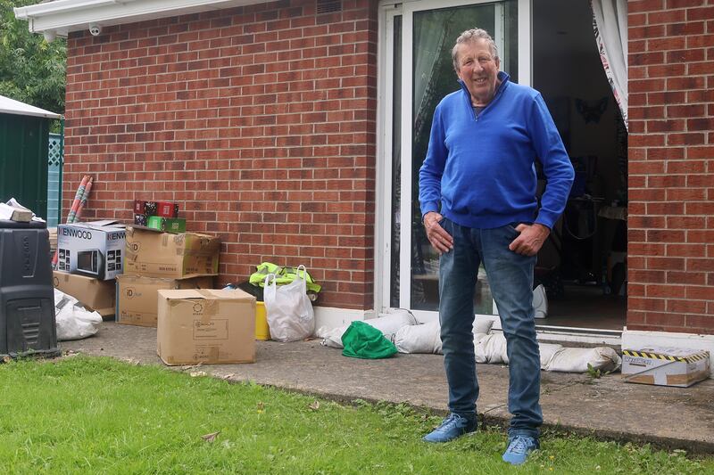Michael Mills outside his home with sandbags at the doorway and some of the possessions he retrieved on Saturday morning.