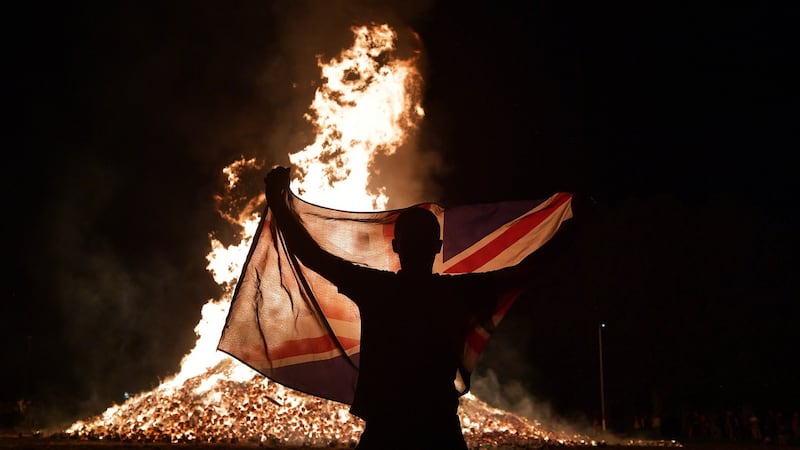 A loyalist waves the  union flag at the Ballycraigy estate 11th night bonfire in Antrim, Northern Ireland. Photograph: Getty