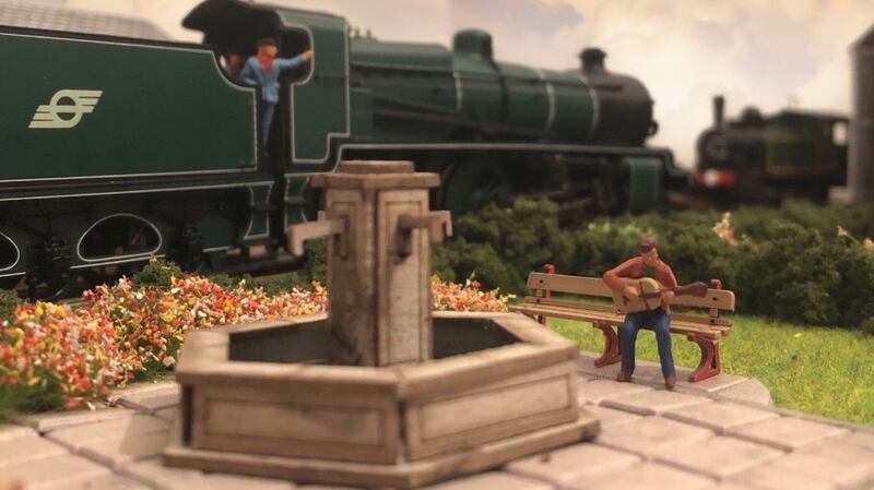 Building model railwats lets us create scenes like this -  a solo bukser playing by the park fountain as an engine passes behind. Photograph: Glen Murphy
