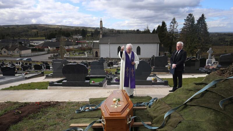 Fr Gerard Alwill blesses the coffin of Fermanagh’s first Covid-19 victim  Anne Best (72) at St Ninnidh’s cemetery. Undertaker Pat Blake stands nearby. Ms Best's husband Tom had to stay away. Photograph: John McVitty