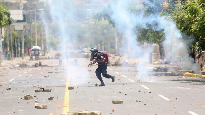 A police officer runs away from homemade mortars launched by demonstrators during clashes in Managua, Nicaragua. Photograph: AP Photo/Alfredo Zuniga