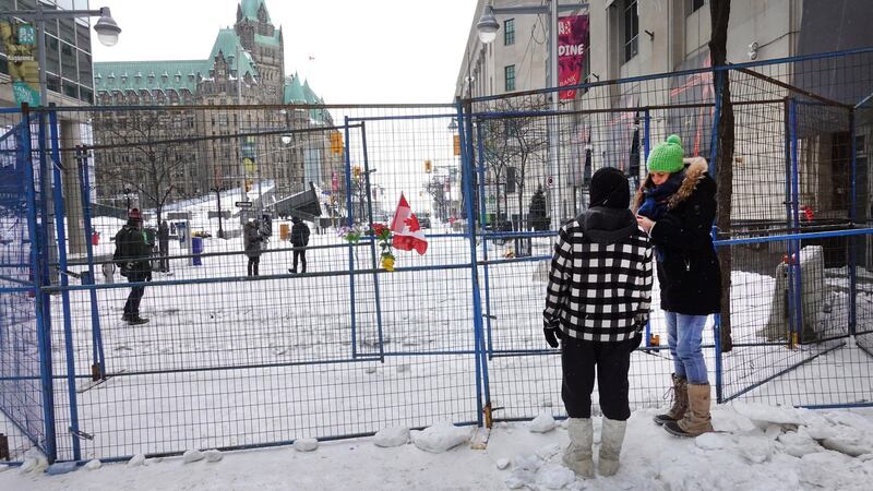 People stand at a barrier fence near Parliament Hill on Sunday, a day after police cleared a demonstration by truck drivers opposing vaccine mandates that had been entrenched for 23 days in Ottawa, Ontario. Photograph: Scott Olson/Getty Images