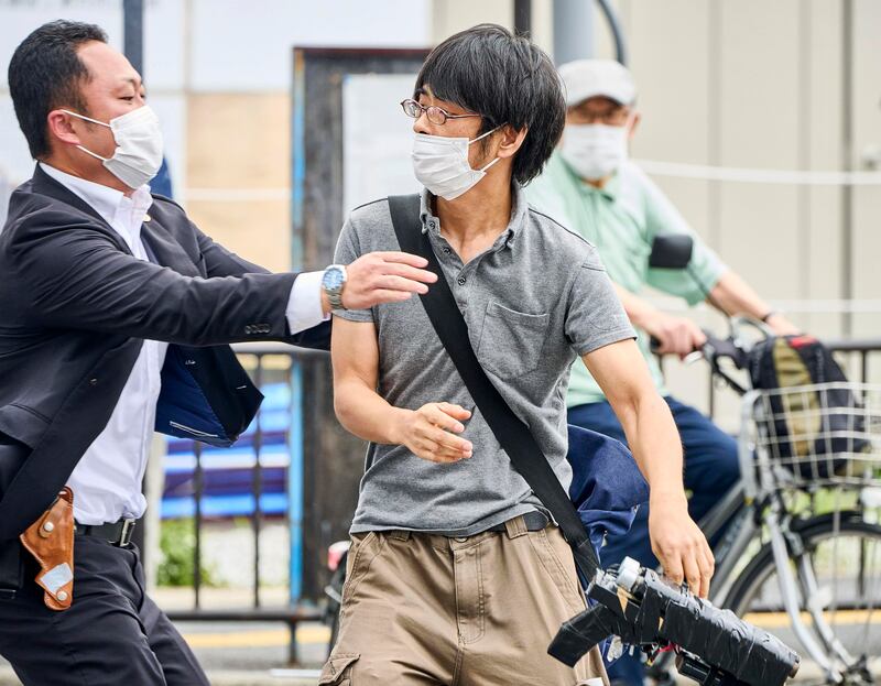 Tetsuya Yamagami, centre, holding a weapon, is detained near the site of the shooting. Photograph: Nara Shimbun/Kyodo News/AP