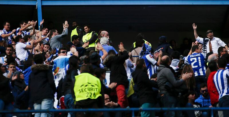 In a mark of solidarity an Atletico Madrid fan  throws his team’s scarf to Deportivo Coruna supporters during their Spanish first division soccer match at Vicente Calderon stadium in Madrid. A Deportivo La Coruna supporter died when dozens of rival fans clashed near the stadium before the game. Photograph: Susana Vera/Reuters