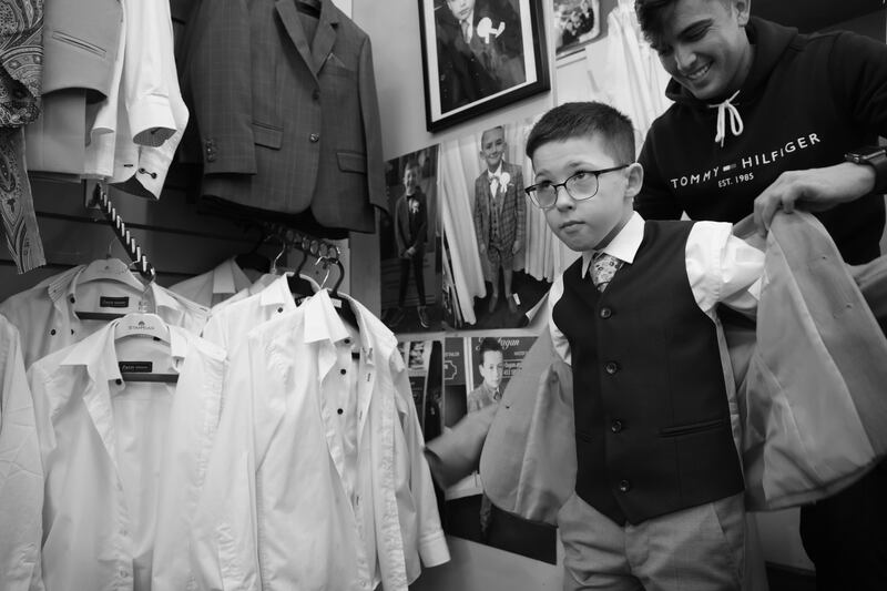 Lewis Fagan helps Cayden Meade (8) as he tries on his new suit. Photo: Bryan O’Brien