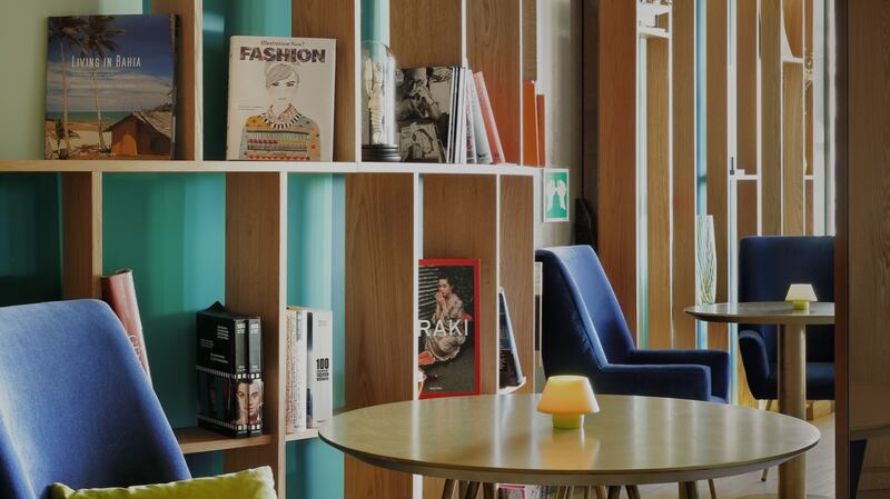 Madrid’s Hotel Indigo:  its lobby is deliberately set out in restful marine shades of blue and green with curved ply shelving lined with books.