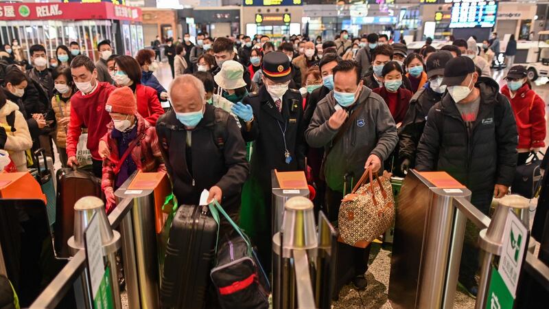 People wearing face masks as a preventive measure against the Covid-19 novel coronavirus walk to a train, one of the stops being Wuhan, at a station in Shanghai on Saturday. Photograph: Hector Retamal/AFP via Getty Images