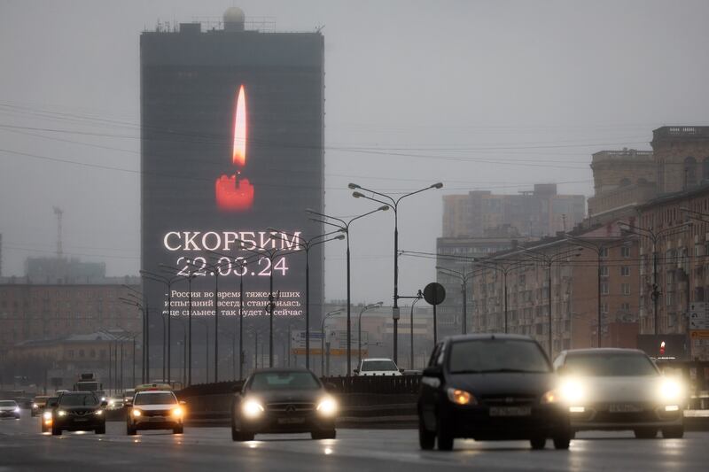 Cars drive past an advertising screen in Moscow displaying an image of a lit candle and the slogan (We) Mourn 22.03.24. Photograph: STRINGER/AFP via Getty Images