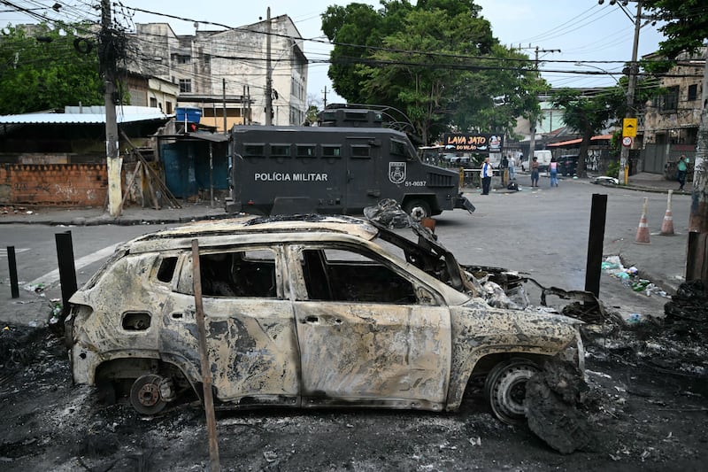An armored military police vehicle stands next to a burned car that was part of a barricade set up during the police operation. Photograph: Mauro Pimentel/AFP via Getty