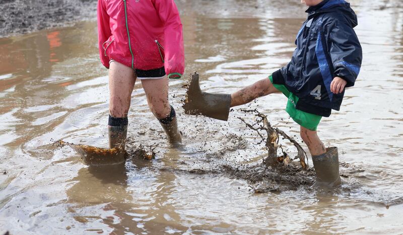 A pair of children splash around in the wet and the mud on day one of the event. Photograph: Dara Mac Dónaill/The Irish Times