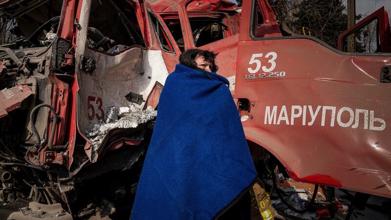A woman covers herself with a blanket near a damaged fire truck after shelling in Mariupol, Ukraine on Thursday. Photograph: AP Photo/Evgeniy Maloletka