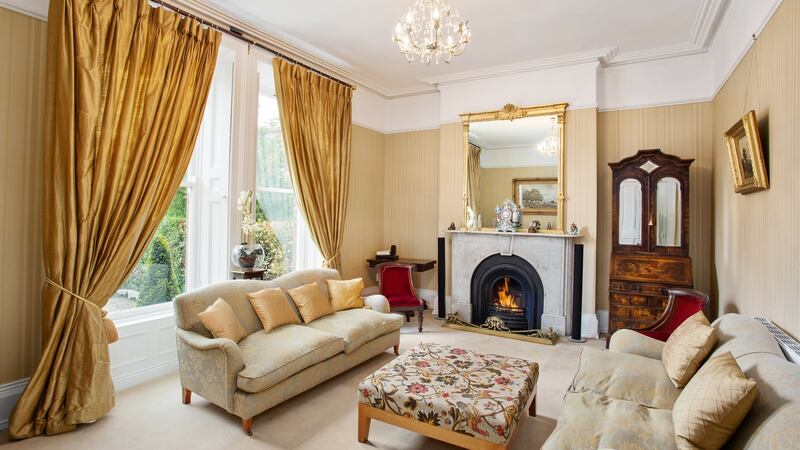 The gracious formal livingroom has two sash windows flanked by original shutters, and  grey marble fireplace