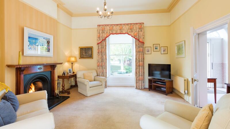 On the right of the front hall is a large living room with a timber fireplace and sash windows with working shutters.