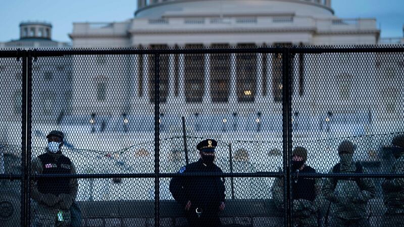 A Capitol Police officer stands with members of the National Guard behind a crowd control fence surrounding Capitol Hill on January 7th. Photograph Brendan Smialowski/ AFP via Getty Images