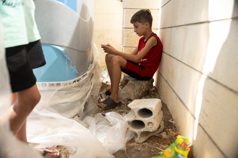 Ten-year-old Hasan El Sayad hides behind the school’s portaloos. Photograph: Chris Maddaloni


