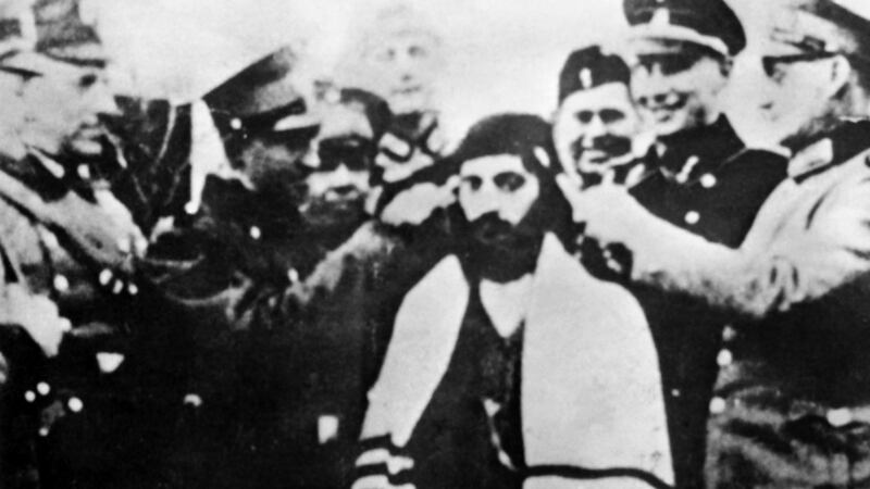 Adolf Eichmann (second from right) smiling while German officers cut a Jewish prisoner’s hair locks in the Bergen-Belsen concentration camp. Photograph: AFP via Getty Images
