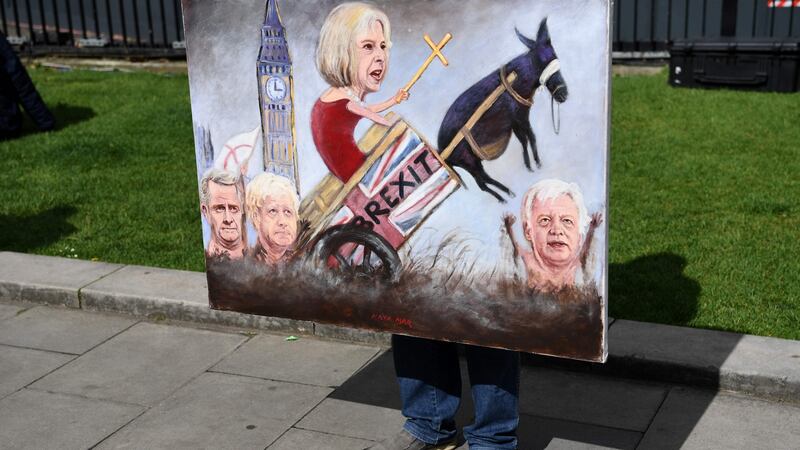 Political artist Kaya Mar holds a painting depicting the faces of British prime minister Theresa May, foreign secretary Boris Johnson, Britain’s secretary of state for exiting the European Union David Davis and international trade secretary Liam Fox, as he stands on College Green, opposite the Houses of Parliament. Photograph: Getty Images