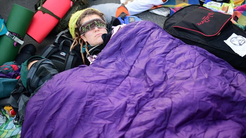 An activist of global environment movement Extinction Rebellion (XR) covers her eyes with a bandage reading “act now” as they block the traffic junction Grosser Stern around the victory column in Berlin. Photo: EPA/Clemens Bilan