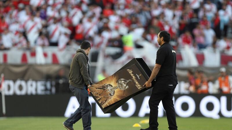 Conmebol employees take away the trophy and its stand. Photo: Juan Ignacio Rocoroni/Getty Images