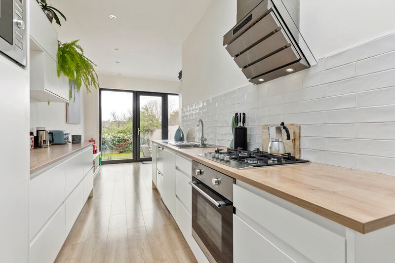 The kitchen is bright, featuring white handleless units with laminate wood-effect countertops