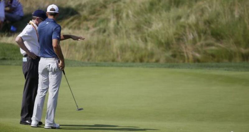 Dustin Johnson talks to a rules official on the fifth green during the final round of the U.S. Open. Photo: John Minchillo