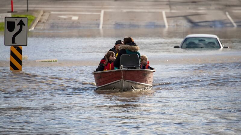 A woman and children who were stranded by high water due to flooding are rescued by a volunteer operating a boat. Photograph: Darryl Dyck/The Canadian Press via AP