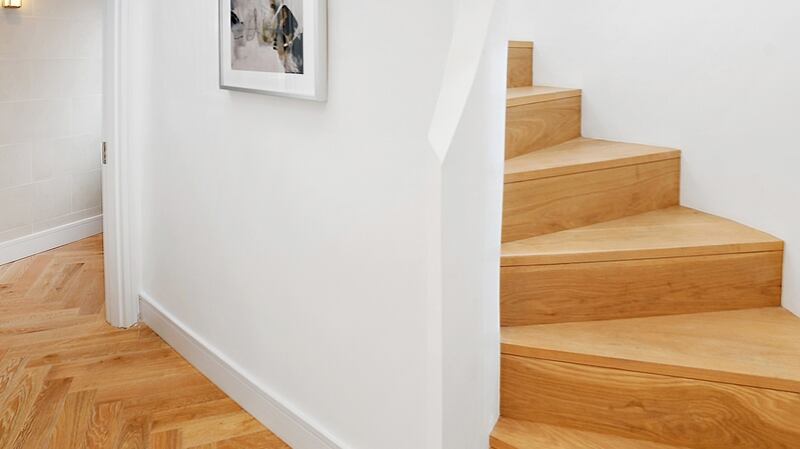Curved oak staircase  illuminated by a large curved window in the stairwell.