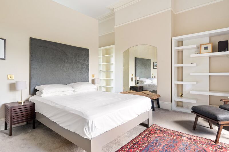 Main bedroom with extensive built-in shelving and wardrobes behind bed