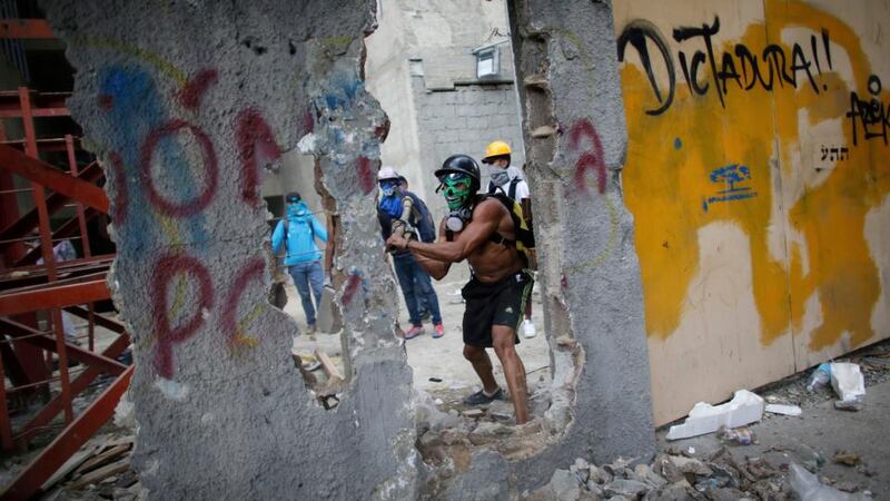 Venezuelan protests: an anti-government demonstrator hits a wall to release pieces of concrete to throw at police in Caracas on Friday. Photograph: Ariana Cubillos/AP