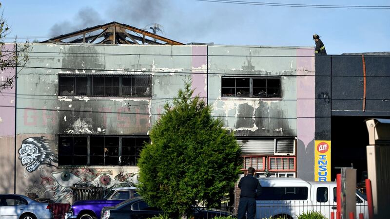 A firefighters walks on the roof of a smoldering building after a fire tore through a warehouse party  in Oakland. Photograph: Josh Edelson/AP.