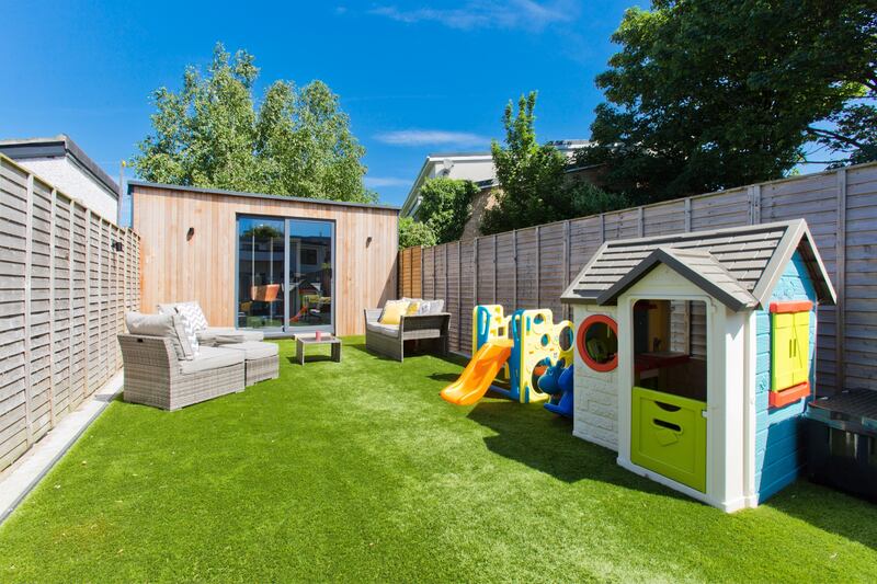 The artificial grass area of the garden, with garden room at the far end.