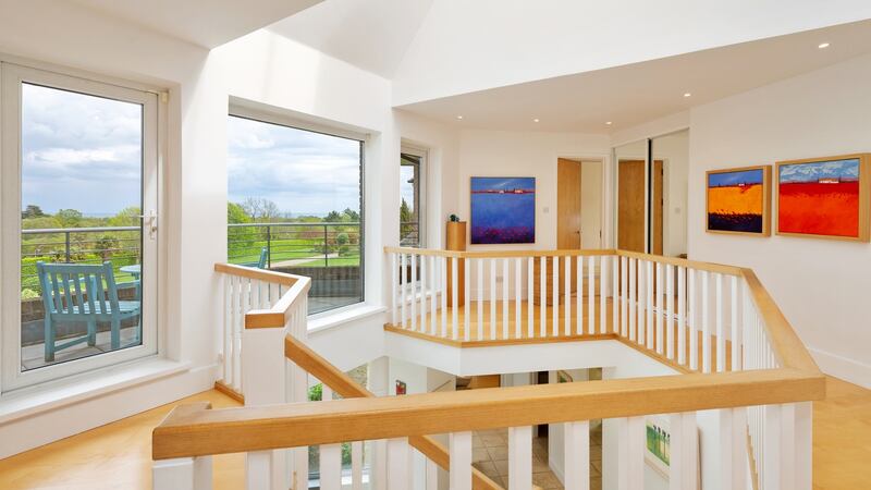 Upstairs the galleried landing has colourful art on the semi-circular wall and a wall of windows with a door opening on to a wide balcony looking over the front lawn towards the sea