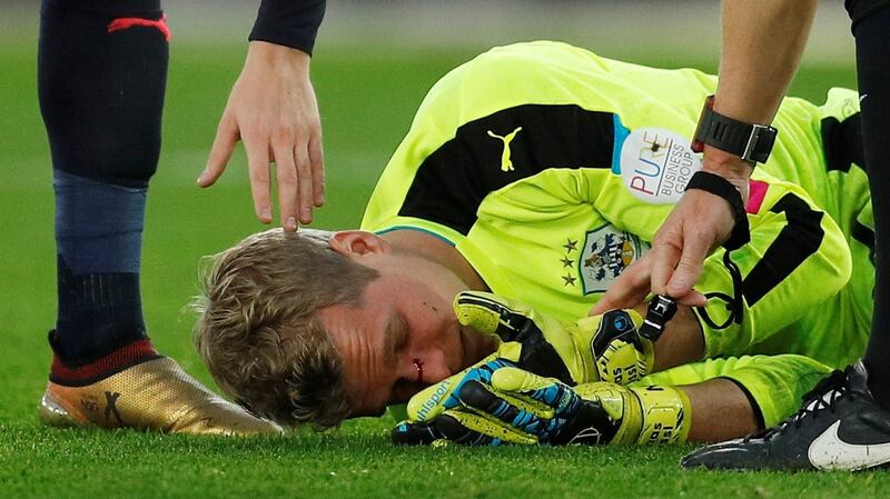 Huddersfield Town goalkeeper Jonas Lossl lies injured after the challenge from Charlie Austin. Photograph:  Peter Nicholls/Reuters