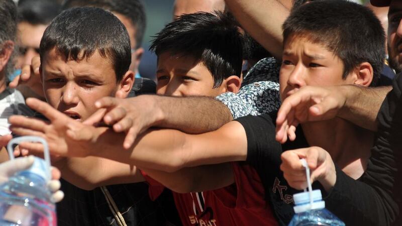 Red Cross workers give out water as migrants and refugees wait under the sun at a railway station, near the official border crossing between Serbia and Croatia, in the eastern Croatian town of Tovarnik. Photograph: Elvis Barukcicelvis/AFP/Getty Images