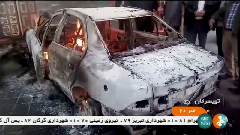 People stand near a burning car in Tuyserkan, Hamadan Province, Iran, December 31, 2017 in this still image taken from video. Photograph: IRINN/ReutersTV via Reuters