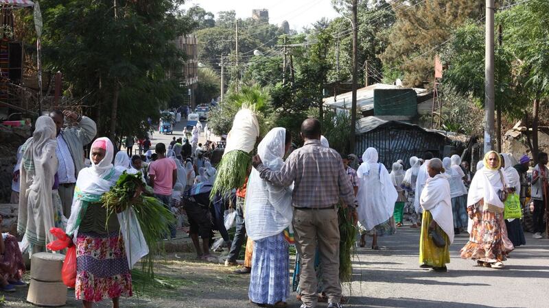 Crowds buying reeds outside a church, a traditional form of decorating floors during holidays and religious festivals-in the distance is the towering 17th-century castle of Emperor Fasiladas rising out of the Royal Enclosure, from where Gondar was once the seat of Ethiopian power and rule. Photograph: James Jeffrey