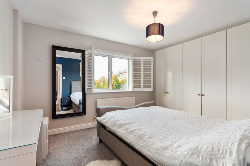 The main bedroom features built-in wardrobes and shutters on the windows.