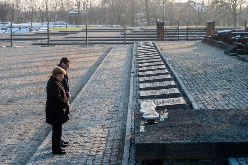 German chancellor Angela Merkel and Polish prime minister Mateusz Morawiecki pay their respects after placing candles at the International Monument Auschwitz II-Birkenau during their visit tot he site. Photograph: John MacDougall/AFP via Getty