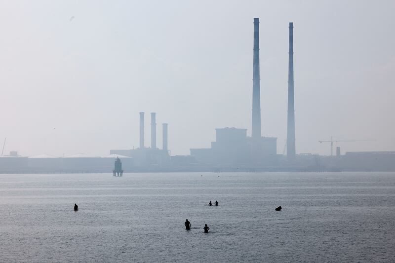 The Poolbeg Chimneys loom through the haze over bathers near Dollymount Beach. Photograph: Alan Betson/The Irish Times

