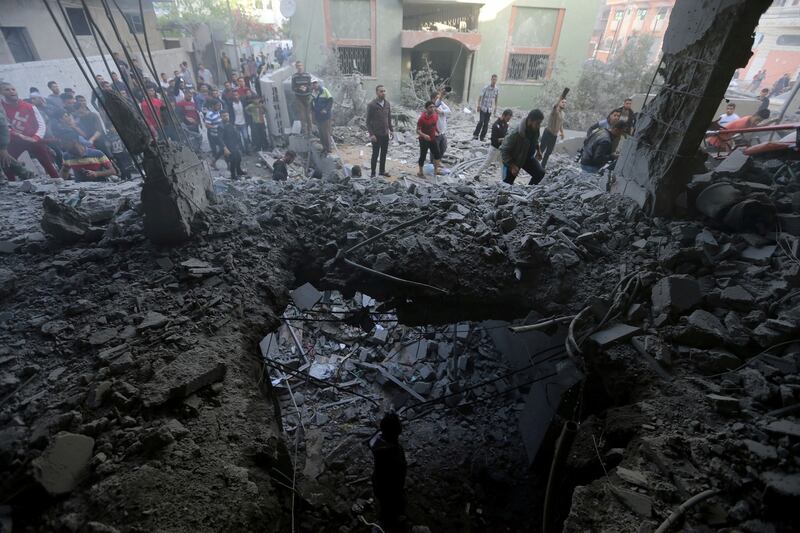 Palestinians gather around a building hit by an Israeli air strike, in the southern Gaza Strip. Photograph: Ibraheem Abu Mustafa/Reuters