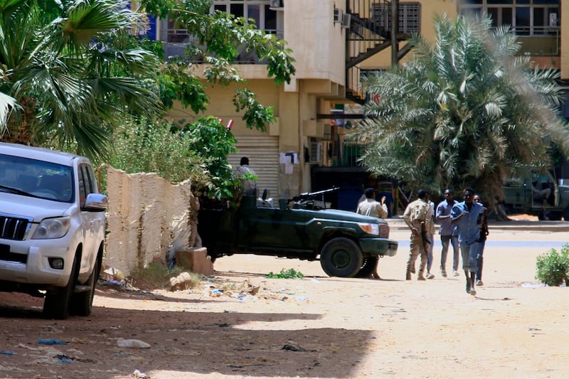 People walk past a military vehicle in Khartoum amid clashes in the city. Photograph: AFP/Getty