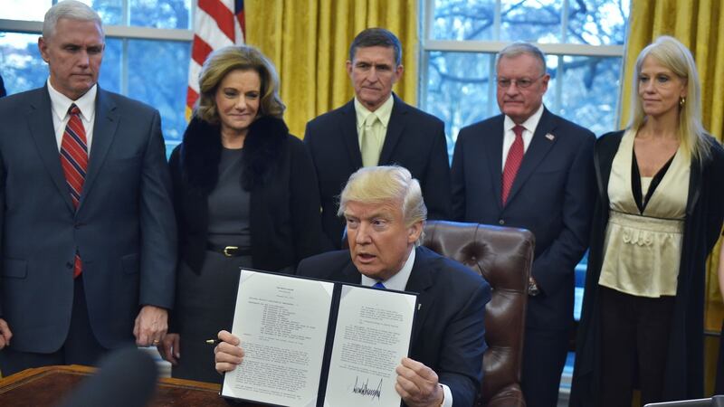 US president Donald Trump holds an executive order in the Oval Office of the White House last week.   National security adviser Mike  Flynn is standing directly behind the president.
